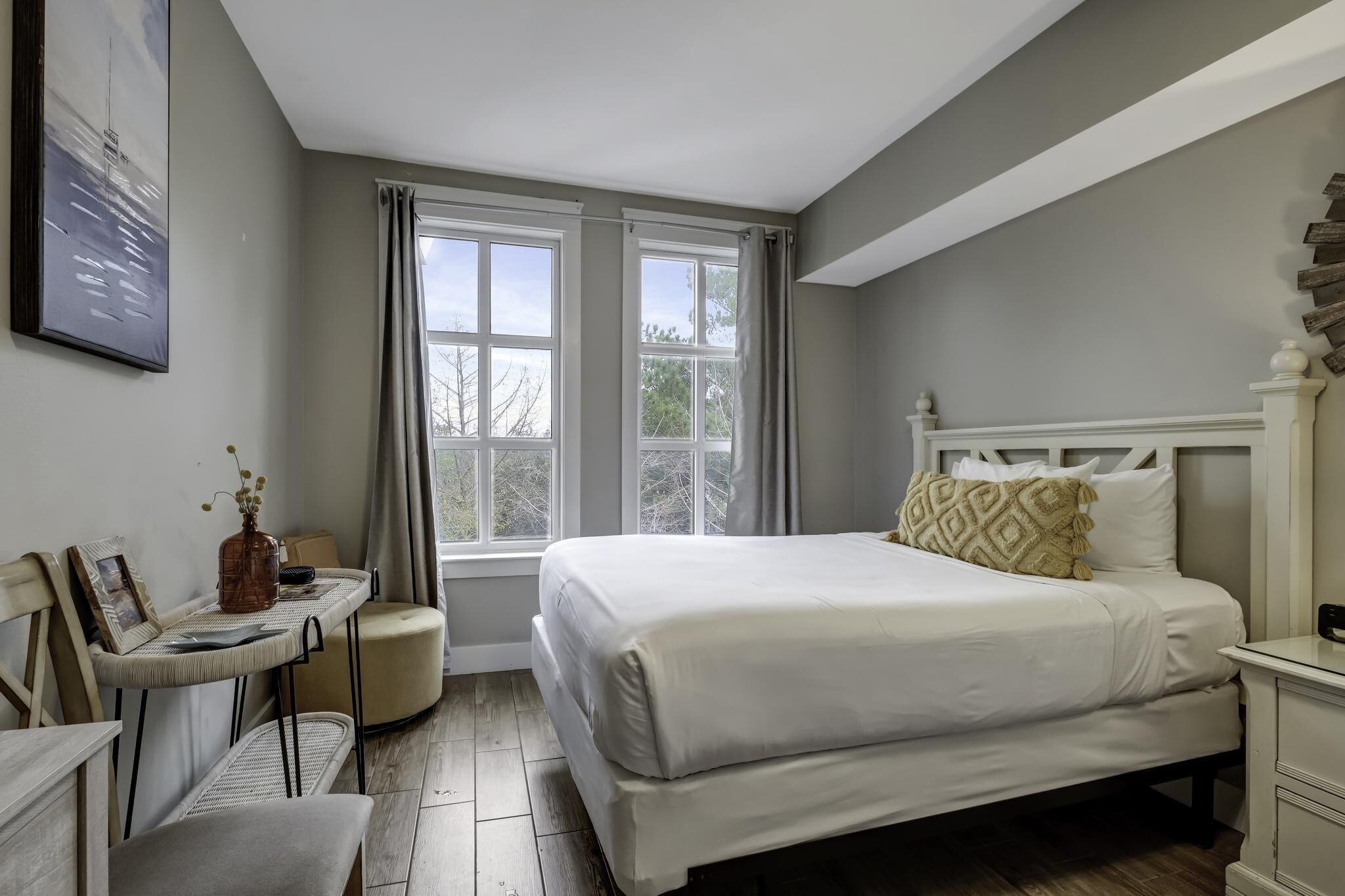 A bedroom with a large bed, a bedside table, a chair, and a window with curtains.