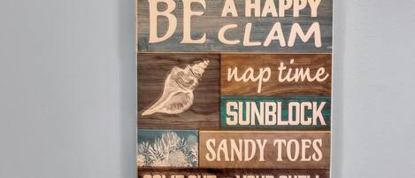 A wooden sign with various phrases related to beach activities.