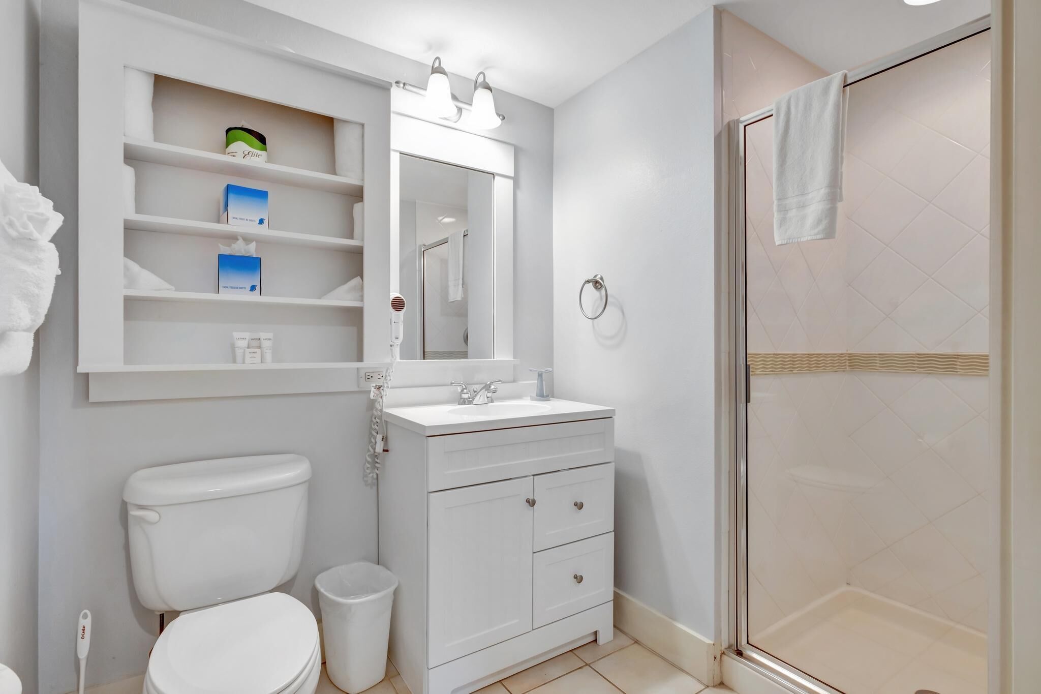 A bathroom with a white toilet, a sink with a mirror above it, and a glass-enclosed shower area.