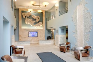 Relax in a stylish lobby with a reception desk, comfortable seating areas, and unique artwork.
