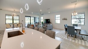 A spacious living area with a large island, modern furniture, and large windows providing natural light. - Alva Vacation Rental w/ Pool & Golf Course Access! (Alva)