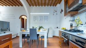 Una cocina moderna con comedor, vigas de techo de madera y salpicadero de azulejos blancos.