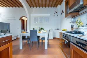 Uma cozinha moderna com área de jantar, vigas de madeira no teto e painel de azulejos branco.