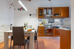 A modern kitchen with wooden cabinets, a dining area with a table and chairs, and decorative wall art.