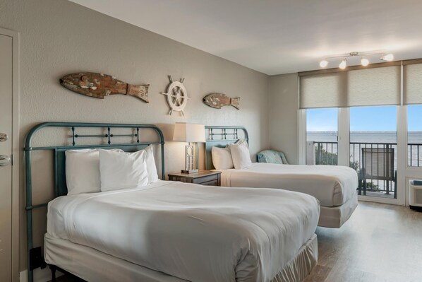A hotel room with two beds, a large window with a view, and nautical-themed wall decor.