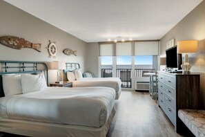 A hotel room with two beds, a balcony with a view, a desk, and a TV.