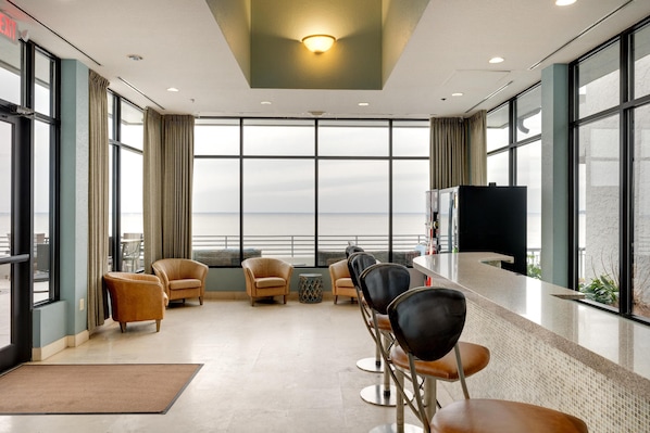 A modern hotel lobby with a long reception desk, comfortable seating, large windows, and a view of the cityscape. - Tranquil Studio with Resort Views - Perfect for Four at Sandestin Golf and Beach Resort! (Miramar Beach)