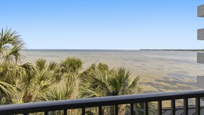 Een balkon met uitzicht op het strand en palmbomen.