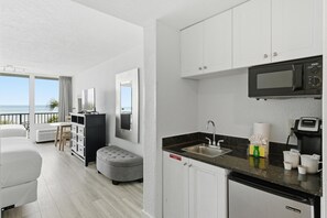 A modern kitchen with white cabinets, a black microwave, and a sink.