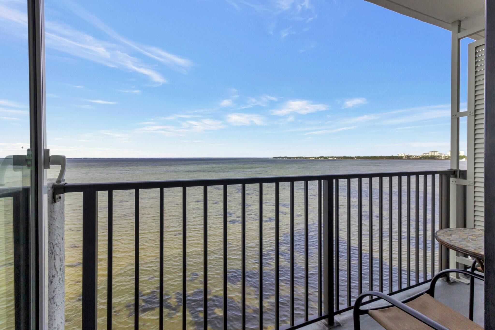 A balcony with a view of the water and distant shoreline.