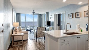 Una sala de estar moderna con vista al océano, un comedor y una cocina con una isla grande.