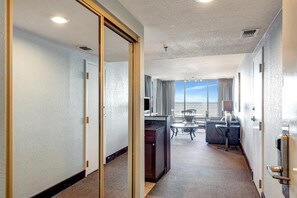 Hotellihuone, josta on näkymä merelle, ja jossa on työpöytä, tuoli sekä pieni pöytä, jossa on lamppu.