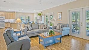 A spacious living room with a grey sofa set, a coffee table, and a dining area with a table and chairs. - Spacious 3BR/3BA Home at Sandestin Golf and Beach Resort! (Miramar Beach)