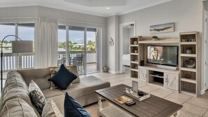 Un salón espacioso con televisor grande, asientos cómodos y un balcón con vistas.