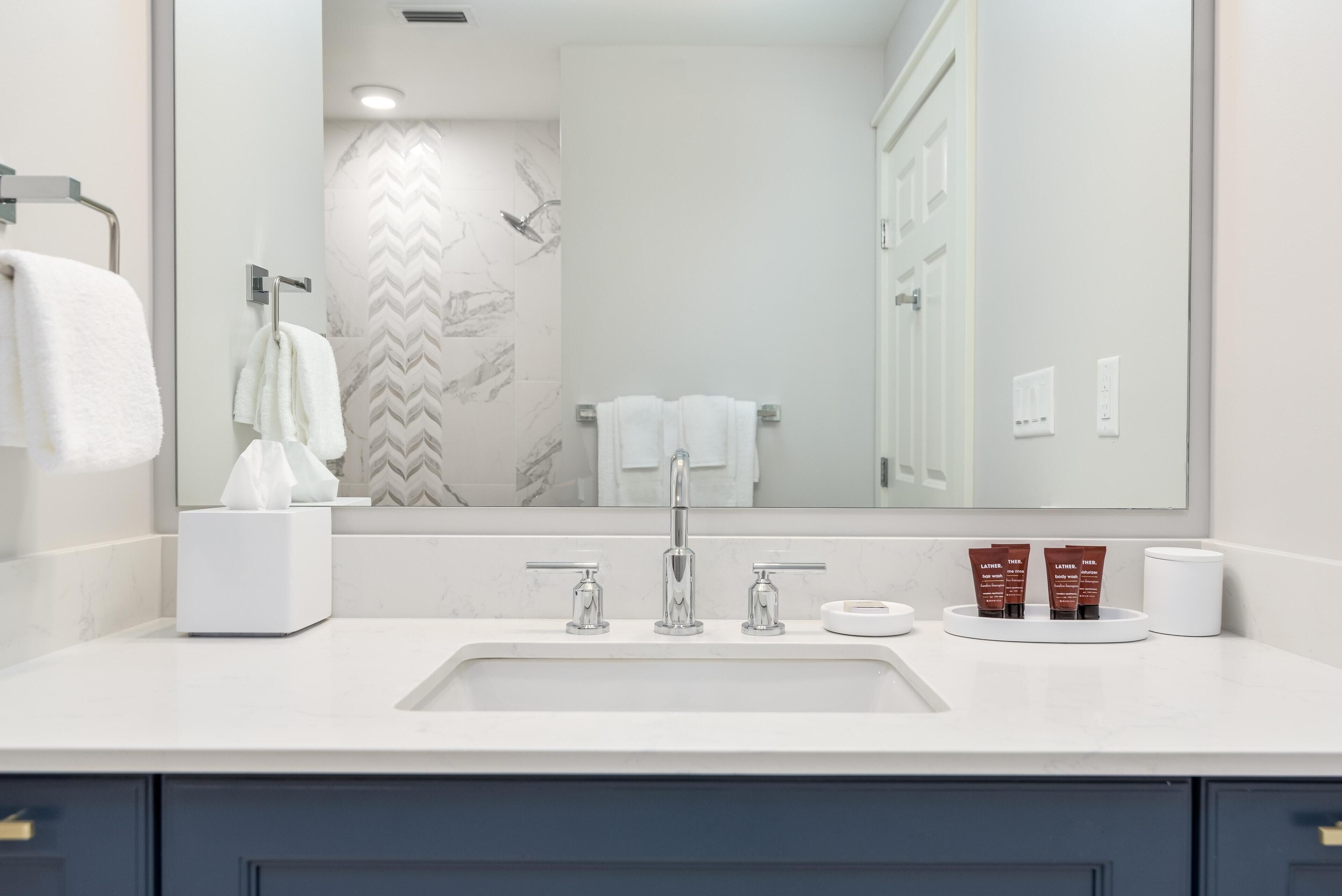 A modern bathroom with a large mirror, a sink with a faucet, and a towel rack.