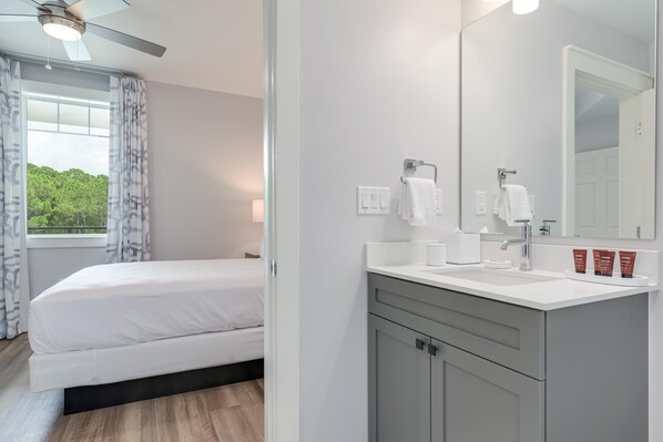 Habitación de hotel moderna con cama, un espejo grande, tocador con lavamanos y ventana con cortinas.
