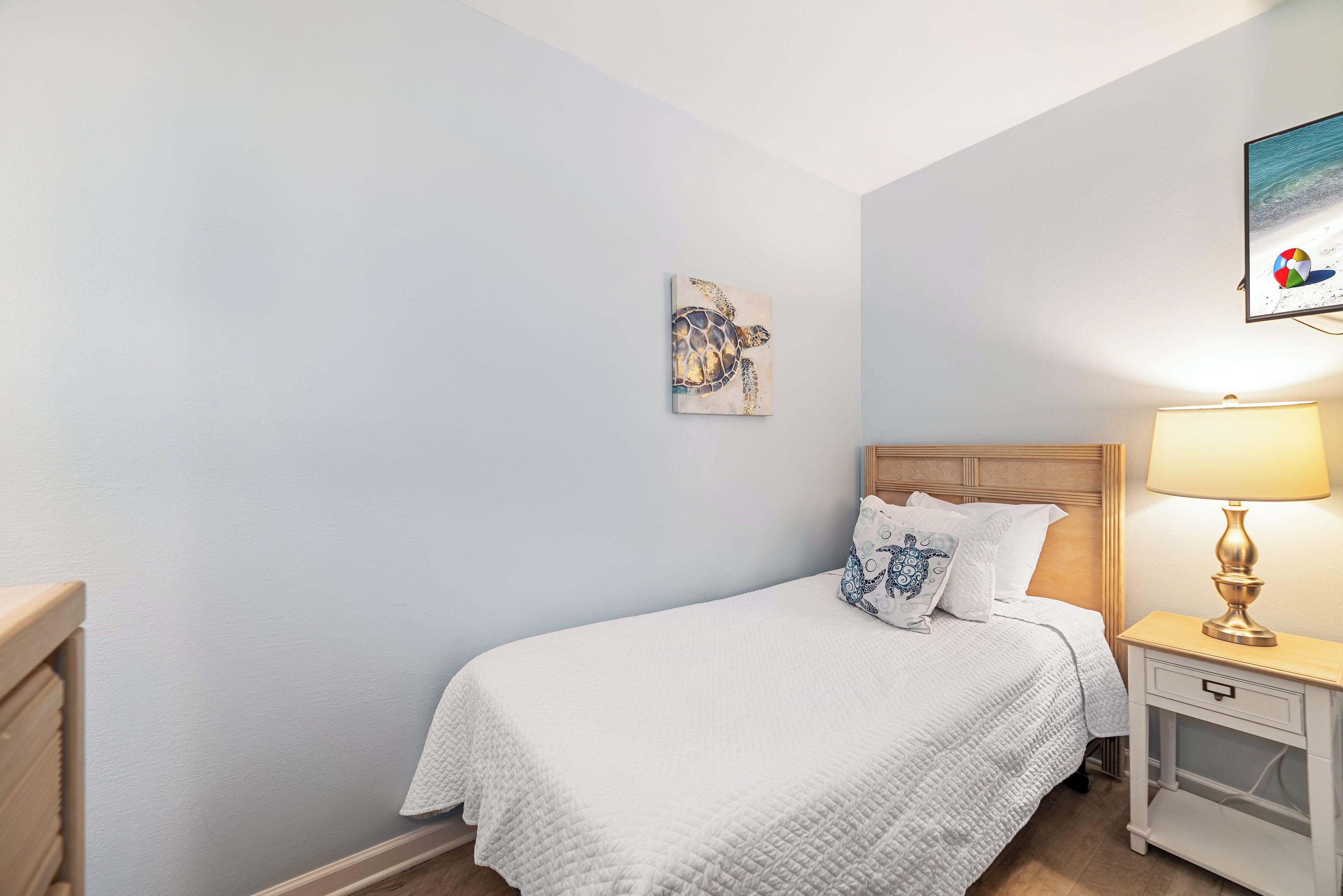 A bedroom with a bed, nightstand, and wall art.