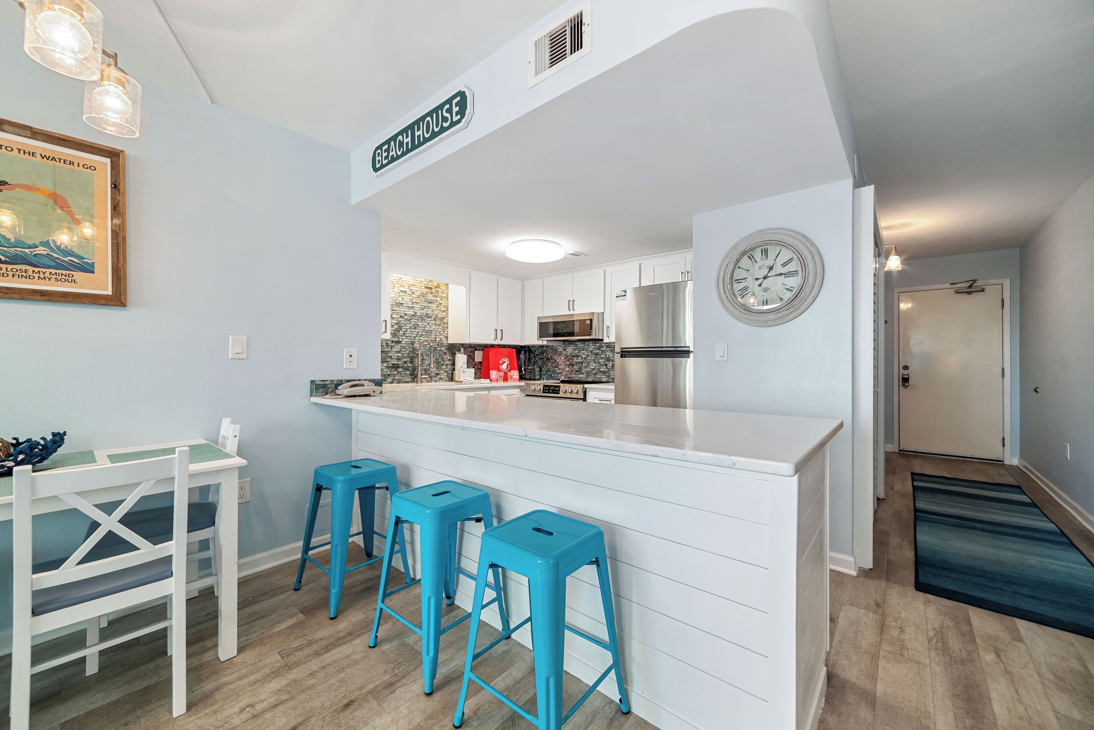 Een moderne keuken met witte kastjes, een roestvrijstalen koelkast en een blauw kookeiland met barstoelen.