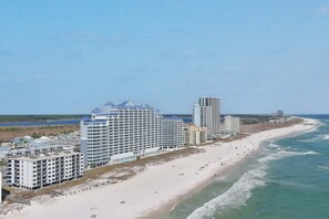 Un hotel frente a la playa con varios edificios altos, una playa de arena y el océano.
