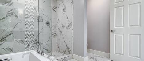 Un baño con bañera, ducha y una puerta blanca.