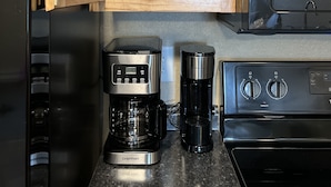 A kitchen with a coffee maker, a blender, and a microwave. - The Petite Perch (Alden)