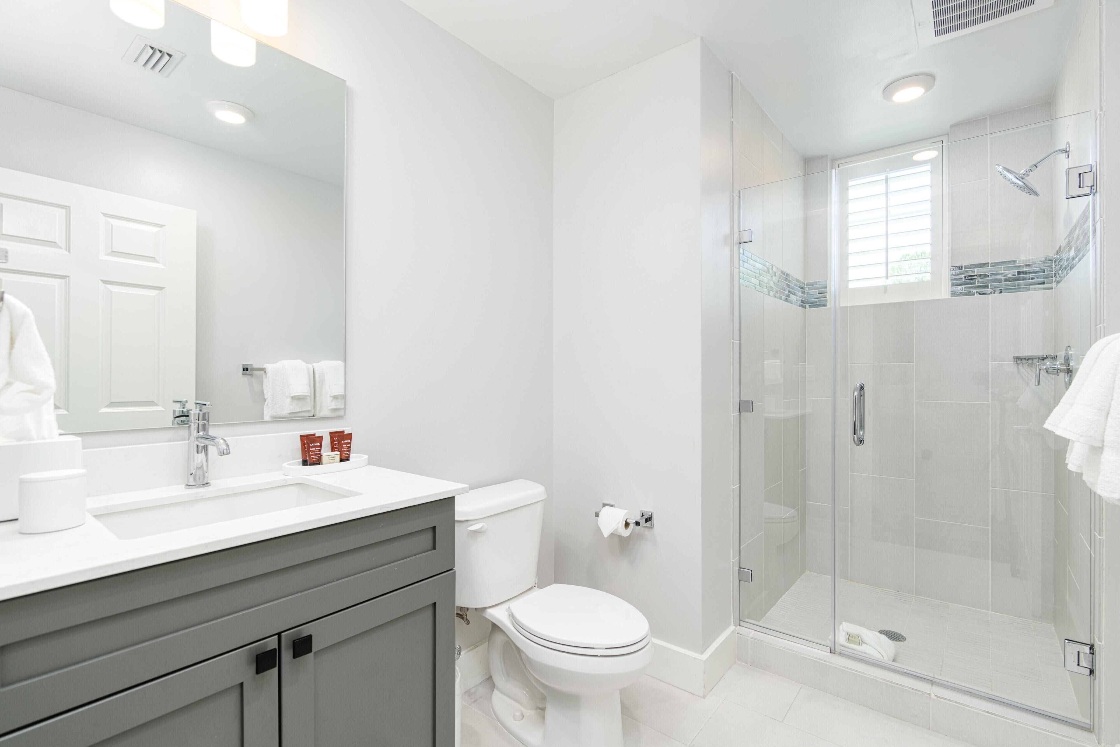 Une salle de bain moderne avec un lavabo, des toilettes et une douche, le tout de couleur blanche.