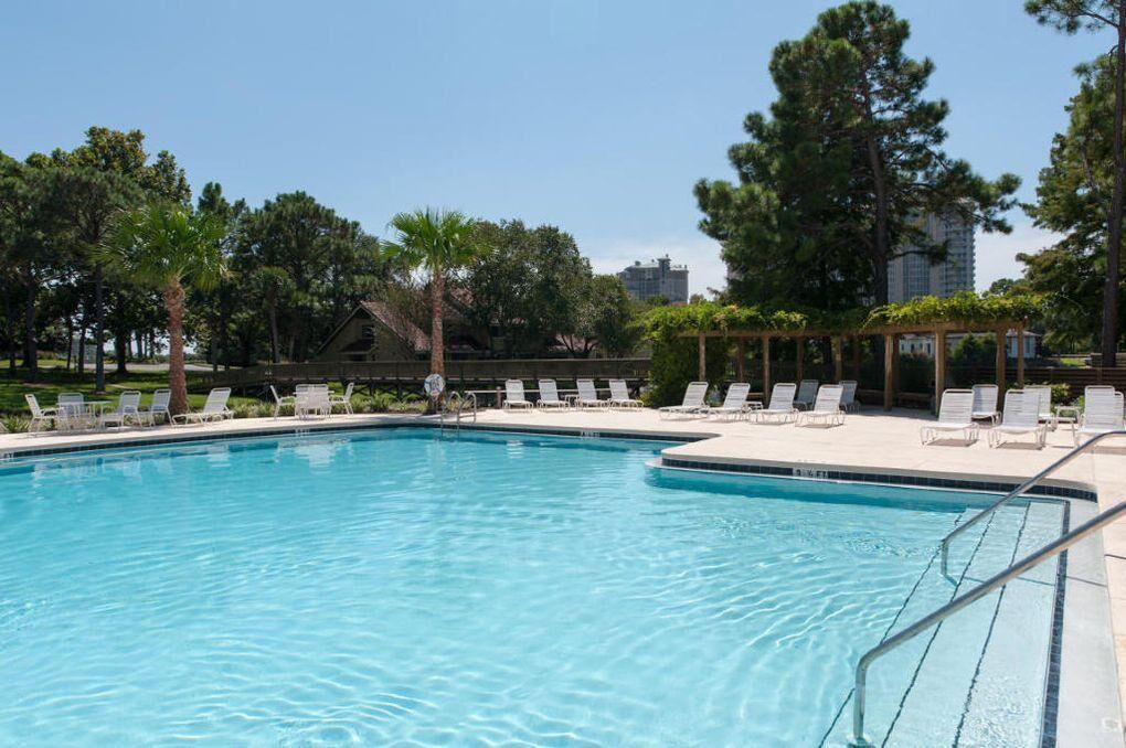 A swimming pool with lounge chairs and a pergola.
