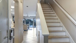 Un interior moderno con una escalera que conduce a un balcón, una zona de cocina y un espacio de estar con vistas.