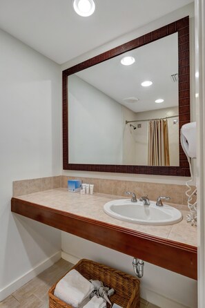 A bathroom with a large mirror, a sink, and a towel basket.