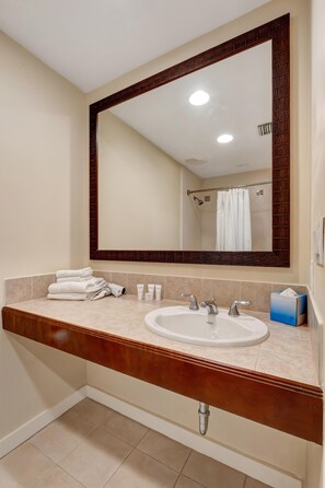 Un bagno con uno specchio grande, un lavandino e una cabina doccia.