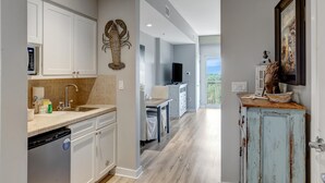 A modern kitchen with white cabinets, a built-in dishwasher, and a dining area with a table and chairs.