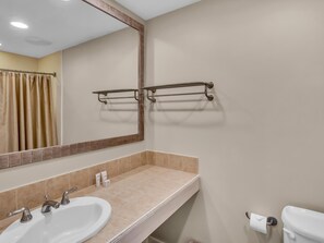 A bathroom with a sink, mirror, towel rack, toilet, and a shower curtain.