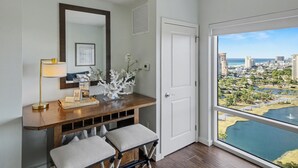 Une chambre moderne avec un bureau en bois, un miroir et une vue sur le paysage urbain, visible à travers une grande fenêtre.