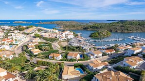 A coastal town with white buildings, a marina, and a clear blue sky. - Villa Alma del Mar - Exceptional Villa with Marina Views & Pool (Minorca)