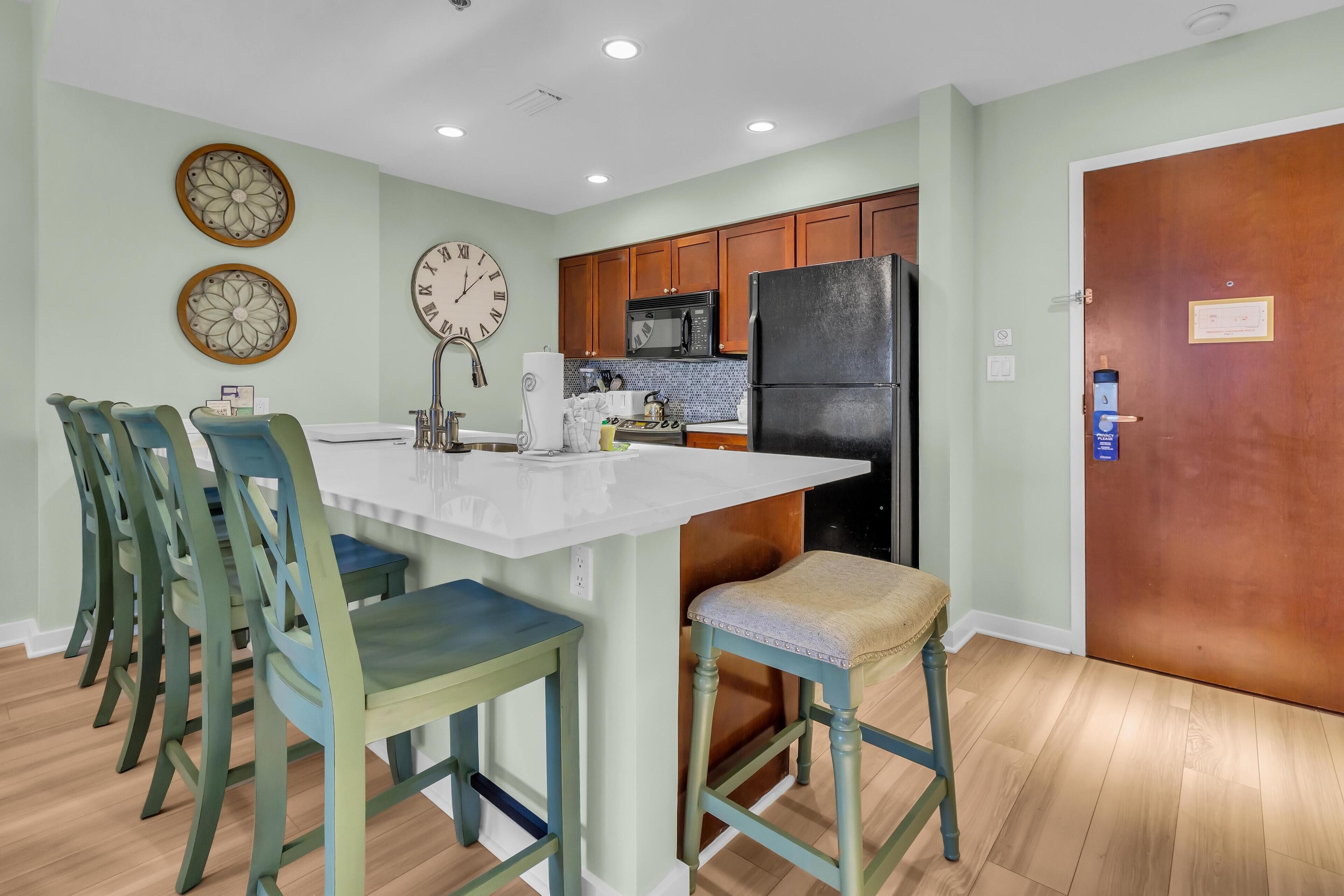A modern kitchen with wooden cabinets, a black refrigerator, and a white countertop.