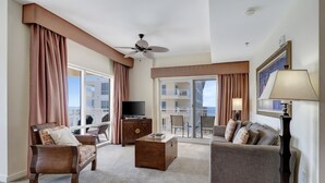 A hotel room with a balcony, a ceiling fan, a TV, a wooden chest, and a sofa. - Charming 1BR Hideaway in Sandestin: Ocean Views, Poolside Bar & Resort Extras (Miramar Beach)
