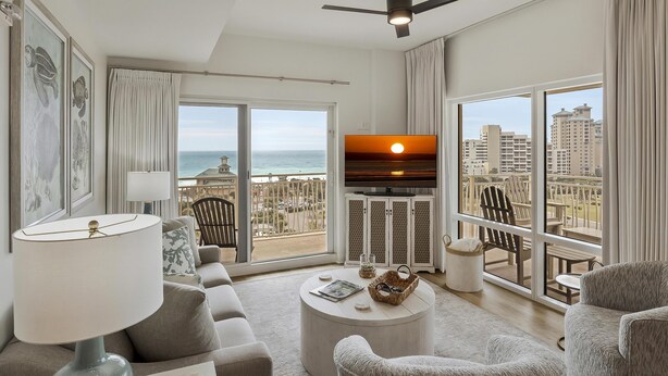 A modern living room with a large window, a ceiling fan, and a flat-screen TV.