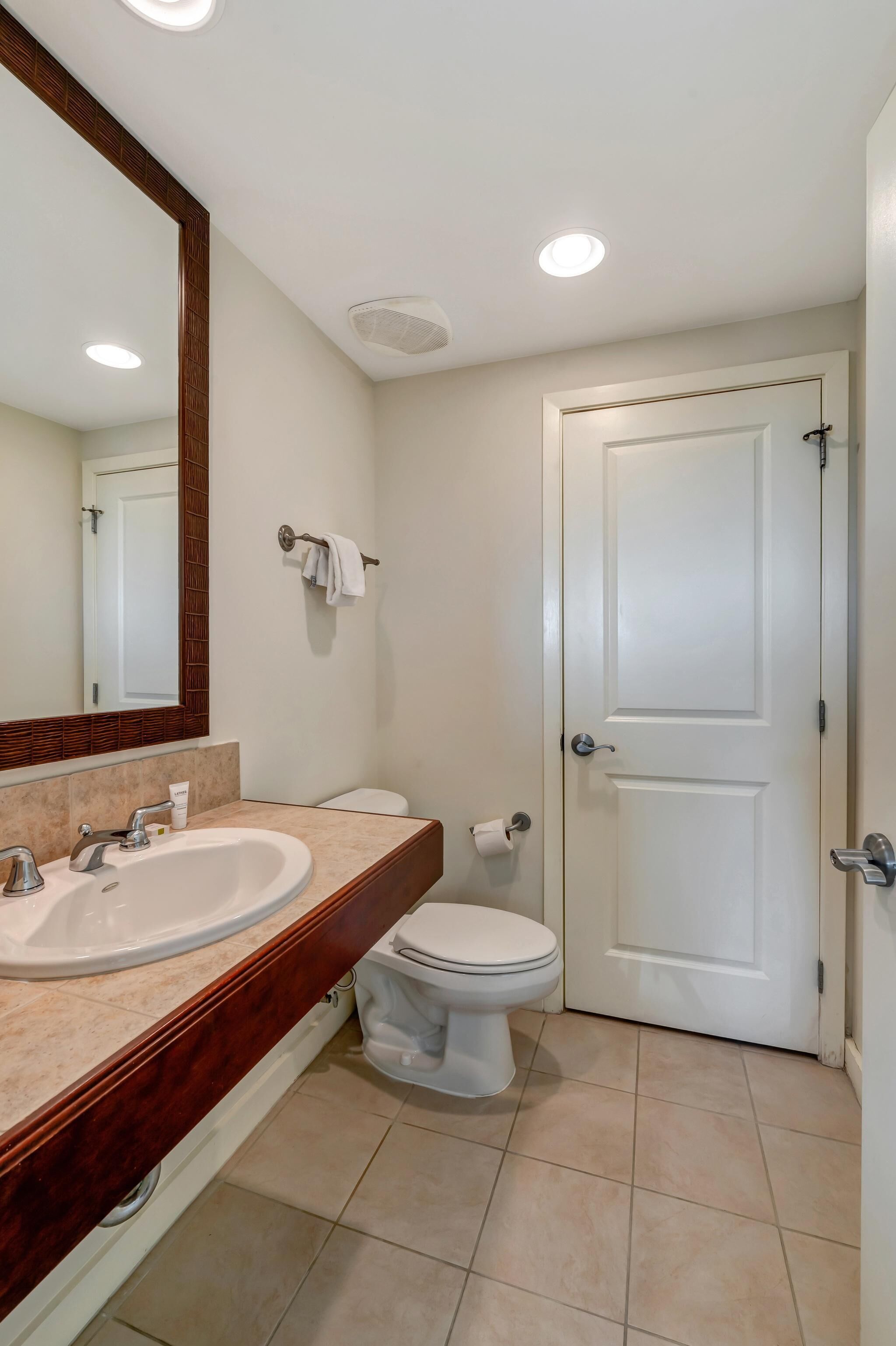 Une salle de bain avec un lavabo, un miroir et des toilettes, le tout de couleur blanche.