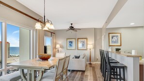 A modern kitchen with a dining area, a bar, and a view of the ocean. - Sandestin Serenity: Luxe 1BR with Scenic Balcony, Sun Deck, Spa Access & Exclusive Perks (Miramar Beach)