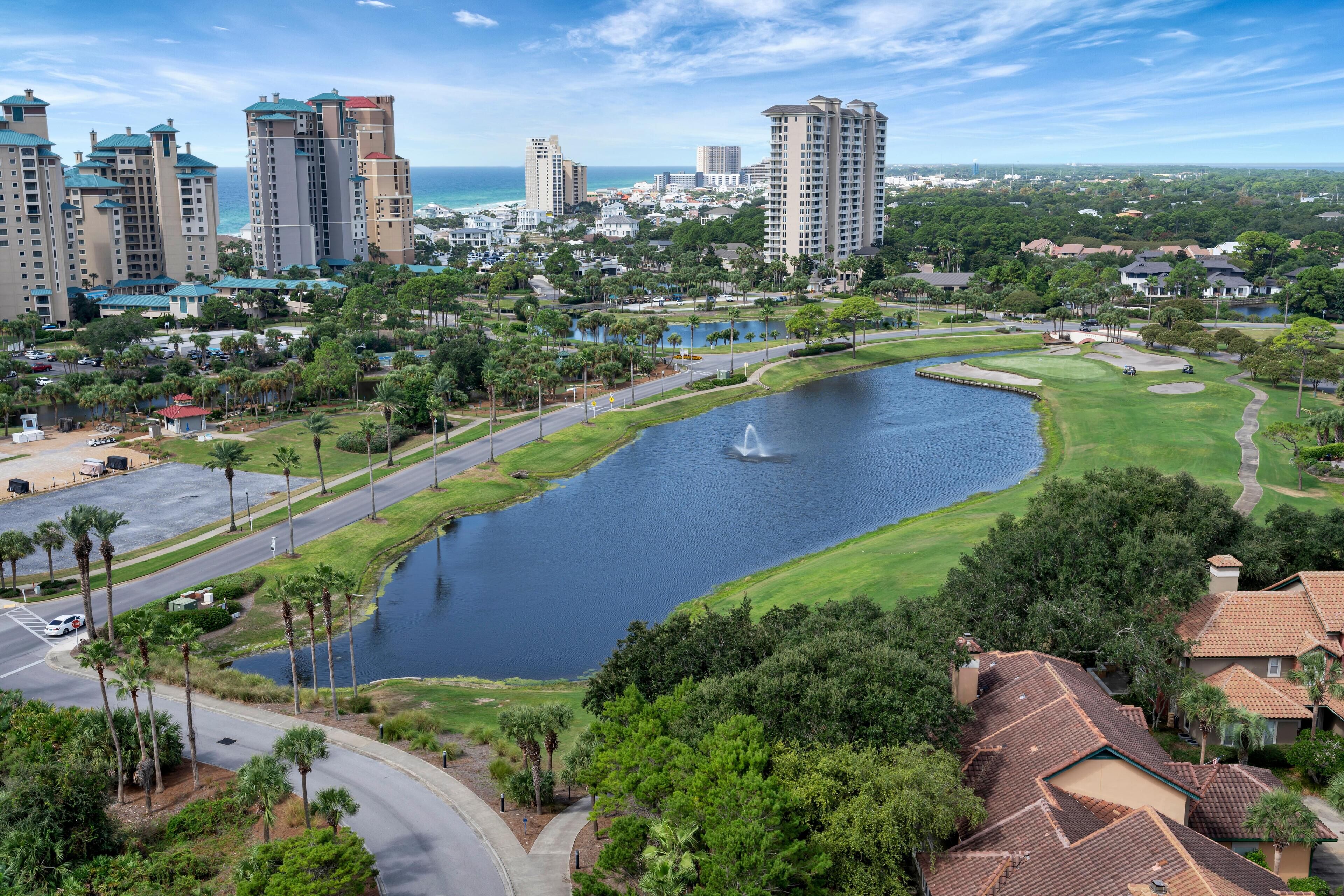 A residential area with a large body of water, palm trees, and high-rise buildings in the background.