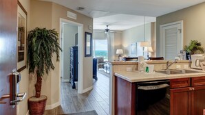 A modern kitchen with a built-in dishwasher, a large island with a sink, and a view to the living area.