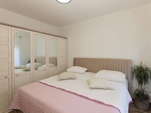 Une chambre à coucher avec un lit, une armoire et une plante en pot.