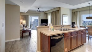 Une cuisine moderne dotée d’un îlot central, d’un coin repas avec une table et des chaises, d’un ventilateur de plafond et d’une grande fenêtre offrant une vue sur la ville.
