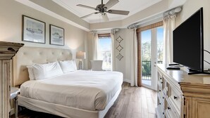 A spacious bedroom with a large bed, a ceiling fan, a television, and a view of the outdoors through a large window. - 3BR/3BA Golf Course View Retreat, Sleeps 6 (Miramar Beach)