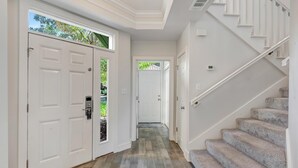 Ein Flur mit Holzboden, einer Treppe und einer Tür mit Zahlenschloss.