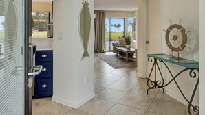 A spacious hallway with a ceiling fan, a fish-shaped mirror, and a ship's wheel decoration. - Charming 2BR Cottage: Sleeps 6 (Miramar Beach)