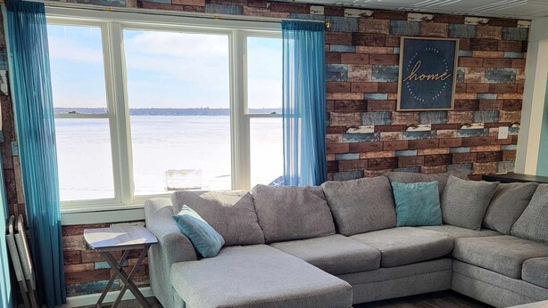 A modern living room with a sectional sofa, a small table, and a view of the water.