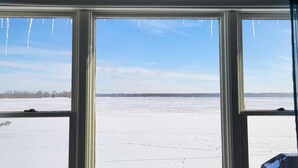 A view through a window with a brick wall above, looking out at a snowy landscape.