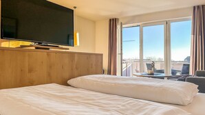 Quarto de hotel com duas camas, televisão e varanda com vista.