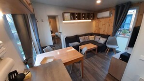 Un espacio habitable compacto con sofá, mesa de comedor y una pequeña zona de cocina.